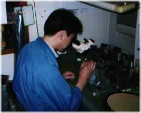 [Ashizawa-San winds a coil for tweeter by hand, looking through a microscope]